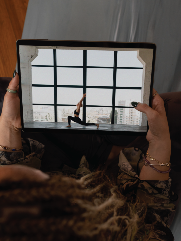 Someone watching a woman instruct exercises on a live stream on the laptop